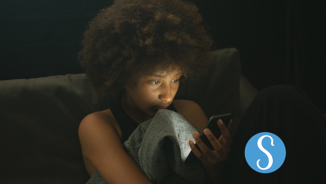 A woman anxiously looking at her phone late at night