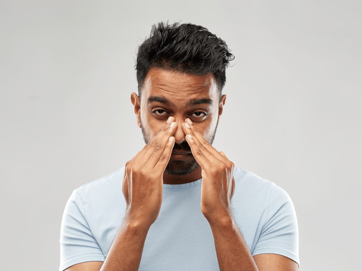 Man suffering from clogged nose and holding sinuses