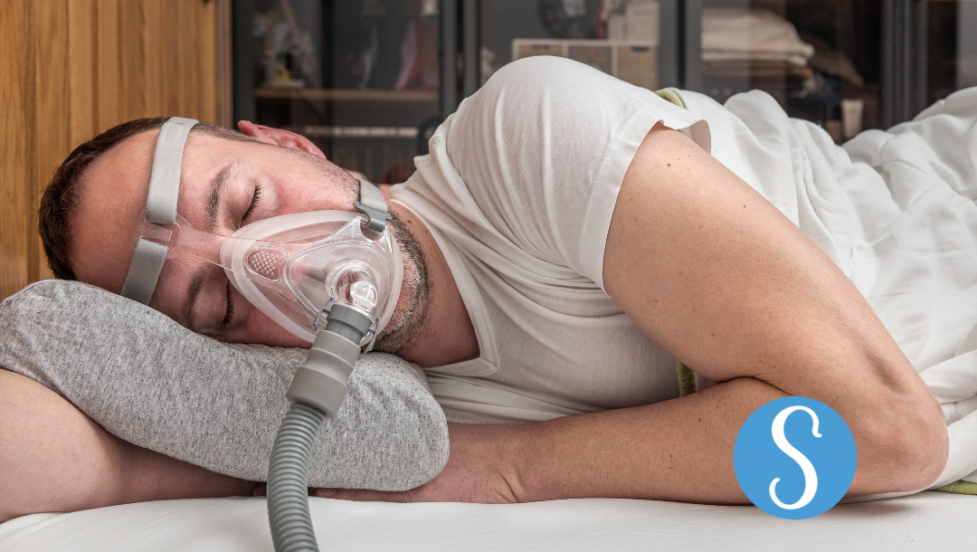 A man sleeping with a CPAP and positional pillow