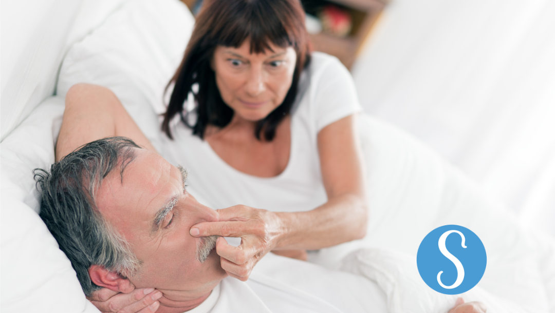 Wife blocking her husbands nose to stop snoring.
