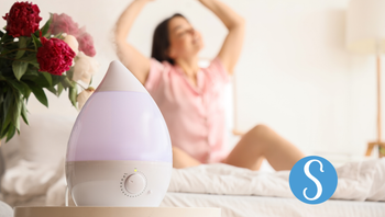 A humidifier with a woman stretching in the background.