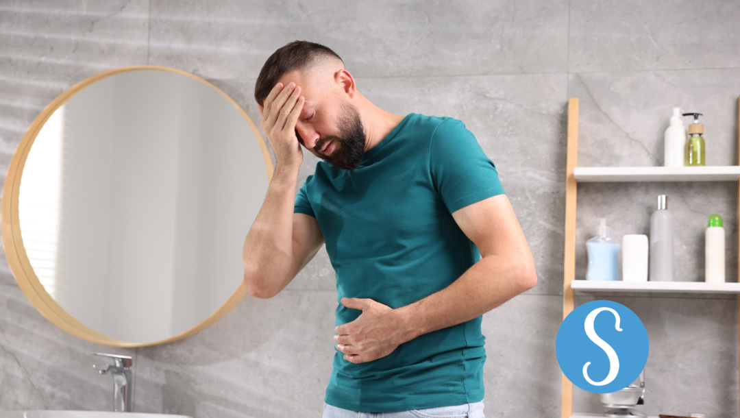 A man feeling nauseous, holding his stomach and head.