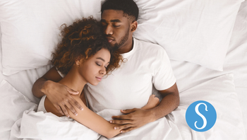 Couple lying in bed, holding each other