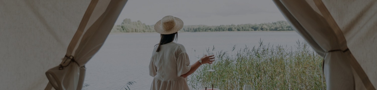 woman looking out at a lake holding a glass of wine